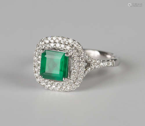 An 18ct white gold, emerald and diamond cluster ring, claw set with a square cut emerald within an