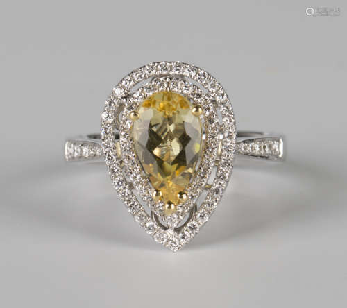 An 18ct white gold, yellow beryl and diamond cluster ring, claw set with a pear shaped yellow