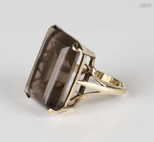 A 9ct gold ring, claw set with a rectangular step cut smoky quartz between split shoulders, detailed