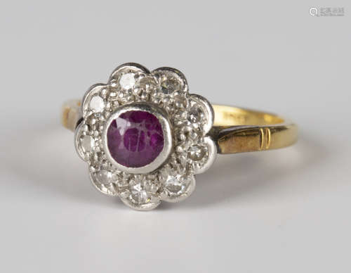 A gold, platinum, ruby and diamond cluster ring, collet set with a cushion cut ruby within a