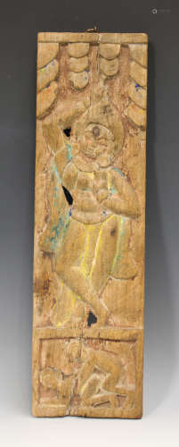 A South-east Asian carved wood rectangular panel, carved in relief with a full-length figure above a