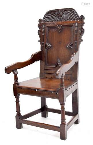 17th century oak wainscot armchair, the rectangular geometric panelled back with a carved cresting