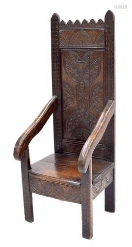 17th century carved oak armchair, the shaped back with arched top carved with flowerhead motif panel