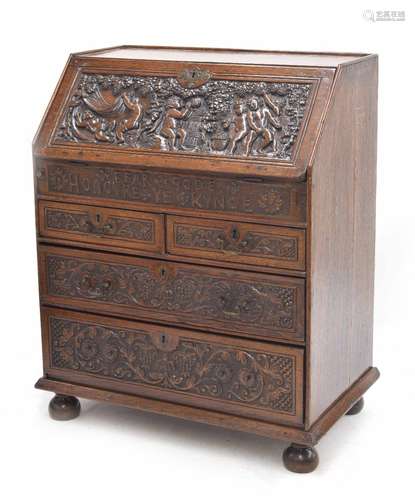 Good early 18th century carved oak bureau, the fall front deeply carved with bacchanalian putti