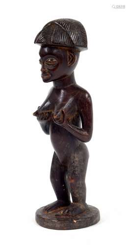 20th century Lwena carved figure of a lady, with angular coiffure, standing on a circular base, 10.