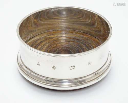 A silver coaster with turned wooden base. Hallmarked Birmingham 1987 maker Argyll Silver. 4