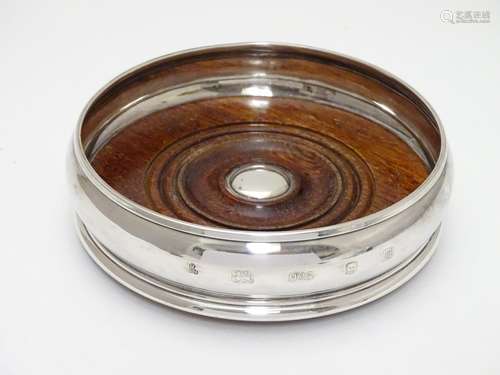 A silver coaster with turned wooden base. Hallmarked London 2003 maker M C Hersey & Son Ltd. Approx.