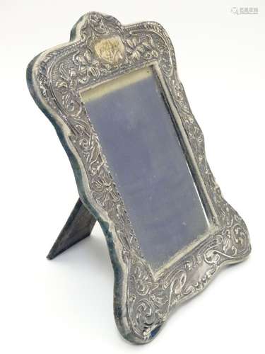 An Art Nouveau photograph frame with silver surround having embossed decoration , on easel style