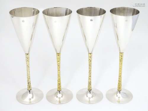 A set of four Elizabeth II silver gilt Stuart Devlin champagne flutes, having flaring conical body