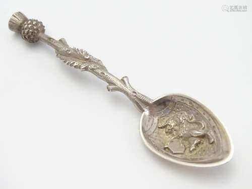 A white metal souvenir spoon with thistle formed handle, lion to bowl and engraved to reverse '