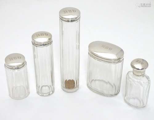 A collection of five silver lidded glass dressing table bottles, all of the silver lids, with the