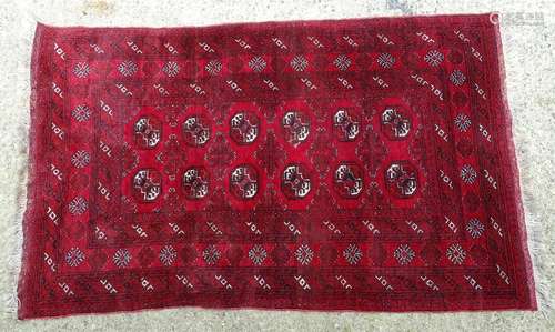 Carpet / Rug : A red ground rug with banded geometric decoration and central repeating medallion and