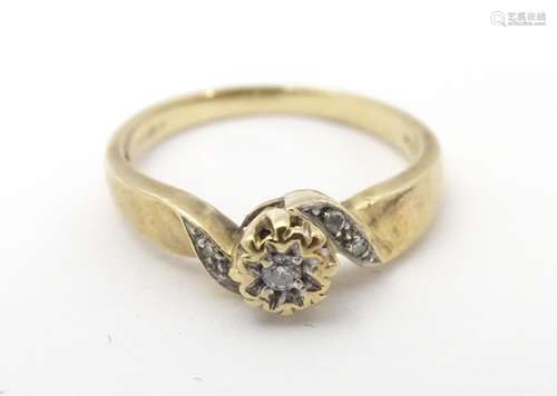 A 9ct gold ring set with central diamond flanked by diamonds to shoulders. Ring size approx J 1/2