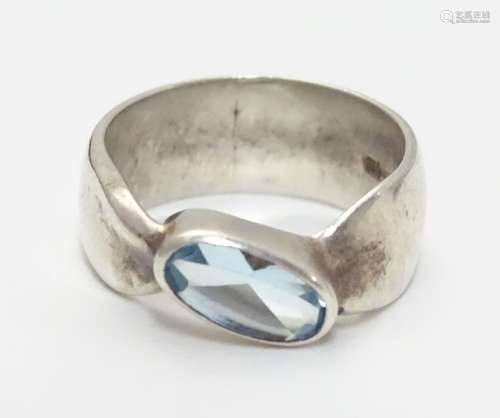 A silver ring set with single oval light blue coloured stone. Rings size approx O Please Note - we