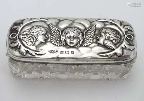 A cut glass dressing table box with silver top having embossed angel decoration. Hallmarked