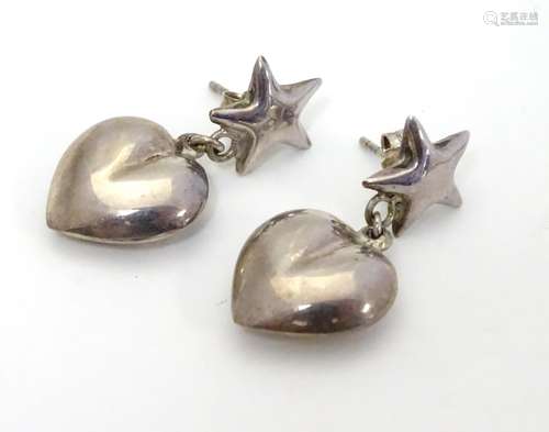 A pair of silver and white metal earrings with heart shaped drops below a star. Stamped 925. Approx.