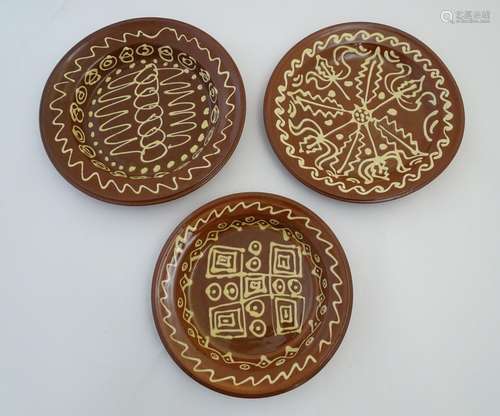 Three 20thC slipware chargers decorated with abstract patterns. One with impressed H maker's mark.