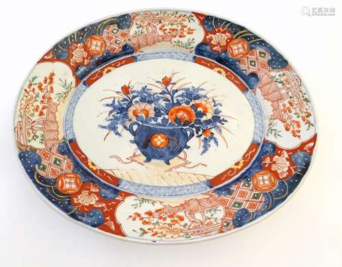 A Japanese Imari style plate, the centre decorated with a vase of flowers with a floral border.