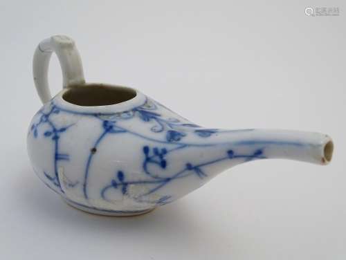A blue and white pap boat with a stylised floral and foliate design with a handle and spout.