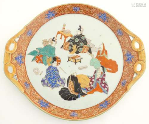 A Japanese twin handled plate with hand painted decoration depicting six seated figures with