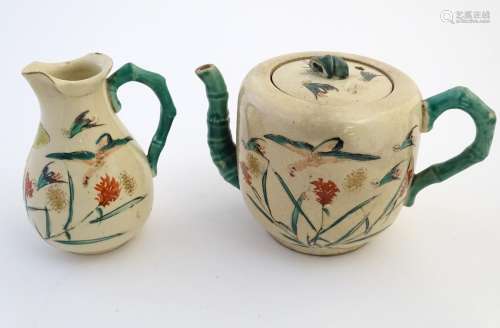 A Japanese teapot and milk jug with hand painted decoration depicting birds and flowers, the handles