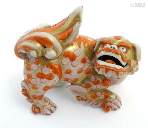 A Chinese ceramic figure formed as a stylised foo dog / temple guardian with gilt highlights.