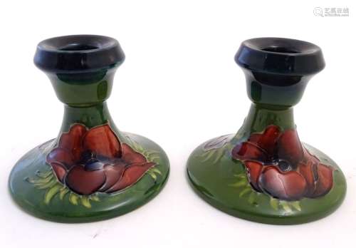 A pair of Moorcroft green ground squat candlesticks decorated with poppy flowers. Impressed marks to