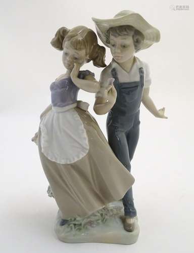 A Lladro figural group depicting a girl and boy with flowers, Love in Bloom, model no. 5292. Approx.