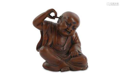 A CHINESE WOOD CARVING OF A BOY CLEANING HIS EAR.