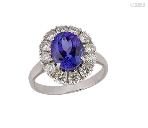 An 18ct. gold, tanzanite and diamond cluster ring, the claw-set oval tanzanite with circular-cut