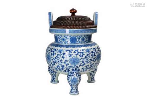 A blue and white porcelain tripod censer with two handles and wooden lid, decorated with lotus