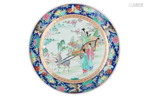 A polychrome porcelain charger, decorated with a landscape with figures on a cart, pulled by a deer.