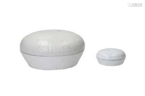 Two round porcelain lidded boxes with relief decor. The larger box of white Kaolin porcelain with