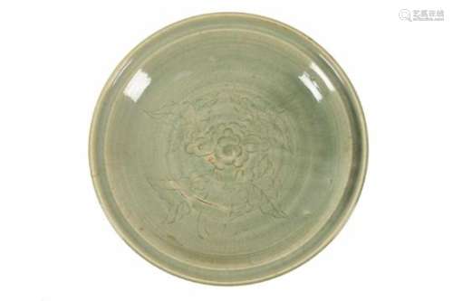 A large celadon glazed porcelain charger with carved decor of a flower. Unmarked. China, 18th