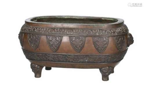 An oval bronze incense burner with archaic and floral decor. The two grips in the shape of masks.