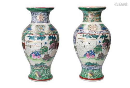 A pair of polychrome porcelain vases, decorated with cranes and figures in mountainous