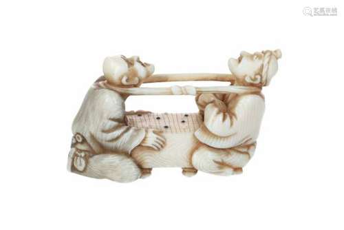 An ivory netsuke of two men playing Go, held together with a cord around their necks. Signed. Japan,