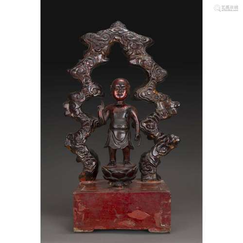 STATUETTE DU BOUDDHA ENFANT en bois laqué rouge et doré, représenté debout sur le lotus, la main droite levée, pointant l'index...