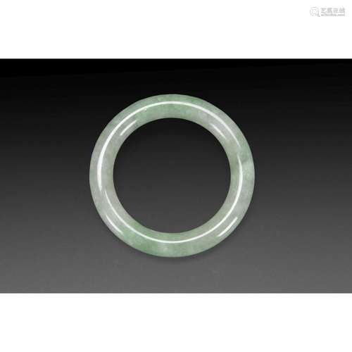 BRACELET en jadéite céladon tachée de vert pomme, de section circulaire, la paroi unie. Chine, XXe siècle. A JADEITE BRACELE...