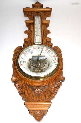 An early 20th Century oak carved cased barometer, the enamel dials with red and black lettering,