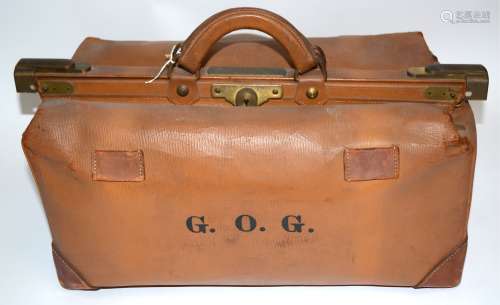 A tan leather Gladstone bag, bearing the initials 'G.O.G', 62cm x 30cm x 30cm