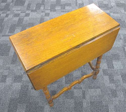 A 1920s honey oak drop flap table, moulded top with rounded corners, turned supports united by