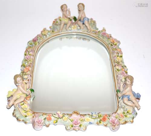 An early 20th Century wall mirror with porcelain surround, surmounted by two cherubs, and with a