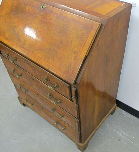 An antique walnut bureau with crossbanding and herring bone inlay, fitted stepped interior, four