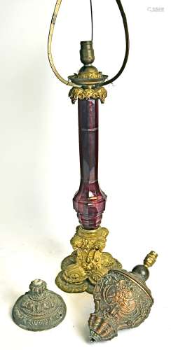 A 19th Century gilt brass lamp base, with cranberry glass central column, raised on a scrolling