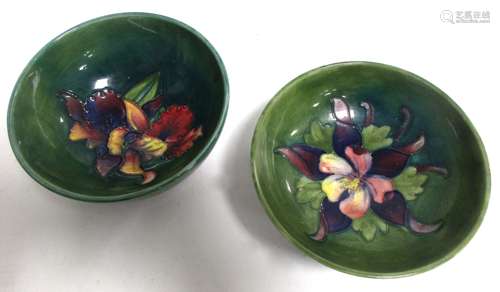 Two Moorcroft Pottery bowls, both with tube lined decoration on green grounds, one with iris or