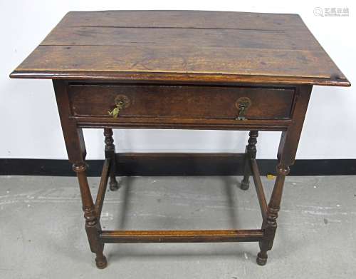 An antique oak side table, three plank top with moulded edge, frieze drawer with brass drop handles,