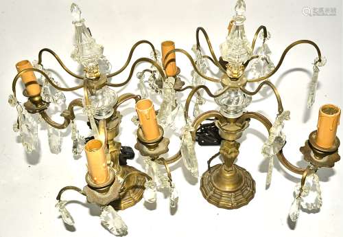 A pair of gilt metal and prism glass table lights, of three branched form, with faceted glass drops,