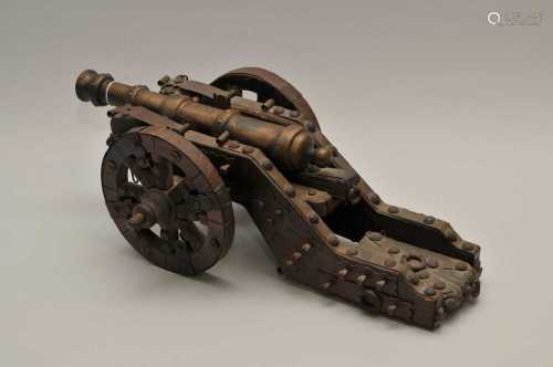 A decorative model cannon, the cast metal gun (32cm long) raised on a stained pine housing, with