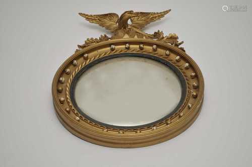 A Regency style convex wall mirror, with a beaded border and carved eagle surmount, 65cm diameter